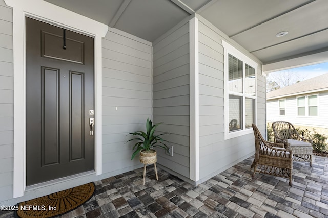 view of exterior entry featuring covered porch