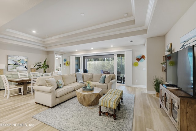 living room with a raised ceiling, crown molding, and light hardwood / wood-style floors