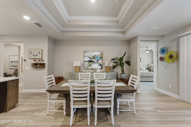 dining space featuring ornamental molding, ceiling fan, light hardwood / wood-style floors, and a tray ceiling