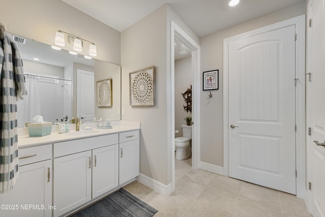 bathroom with vanity, tile patterned flooring, toilet, and walk in shower