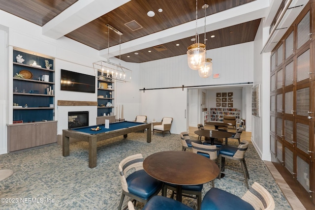 rec room featuring beamed ceiling, a high ceiling, a barn door, wooden ceiling, and built in shelves