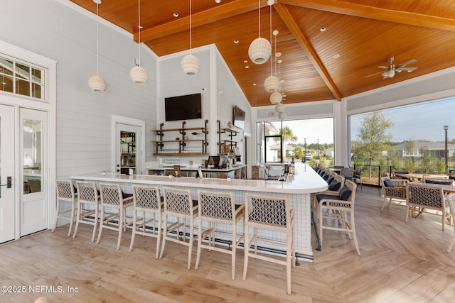 kitchen featuring high vaulted ceiling, wooden ceiling, a kitchen breakfast bar, pendant lighting, and light parquet flooring