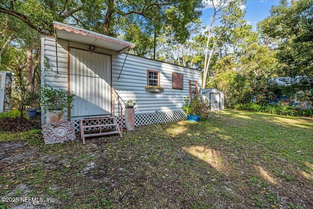 rear view of property featuring a lawn and a storage unit