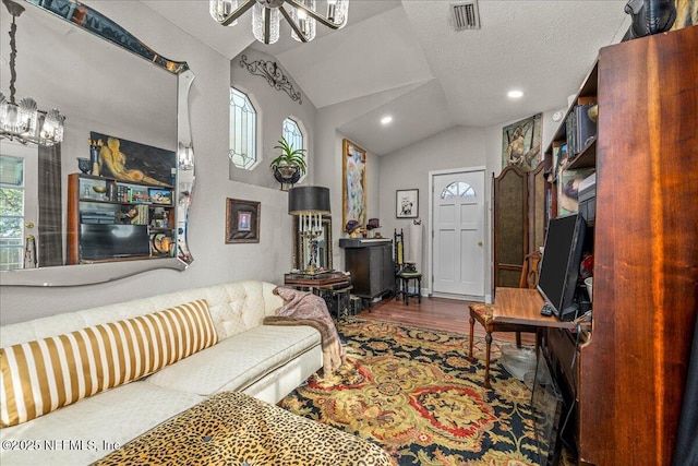 living room with a chandelier, vaulted ceiling, hardwood / wood-style floors, and a textured ceiling