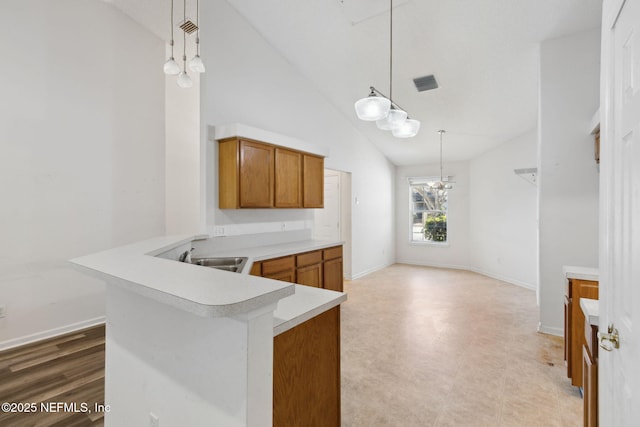 kitchen with sink, hanging light fixtures, high vaulted ceiling, and kitchen peninsula