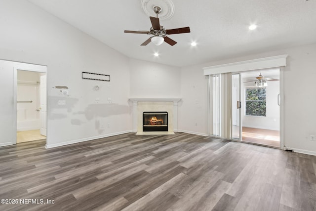 unfurnished living room featuring ceiling fan, lofted ceiling, a premium fireplace, and hardwood / wood-style floors