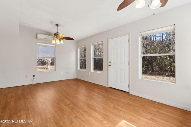 interior space with ceiling fan, plenty of natural light, light hardwood / wood-style floors, and a textured ceiling