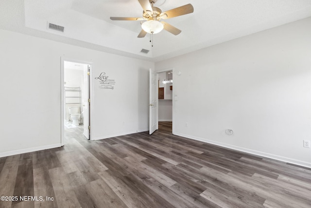 spare room featuring a tray ceiling, dark wood-type flooring, a textured ceiling, and ceiling fan