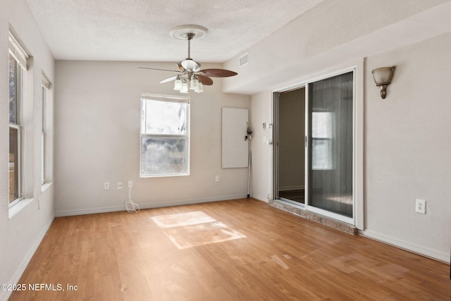 empty room with ceiling fan, a textured ceiling, and light wood-type flooring