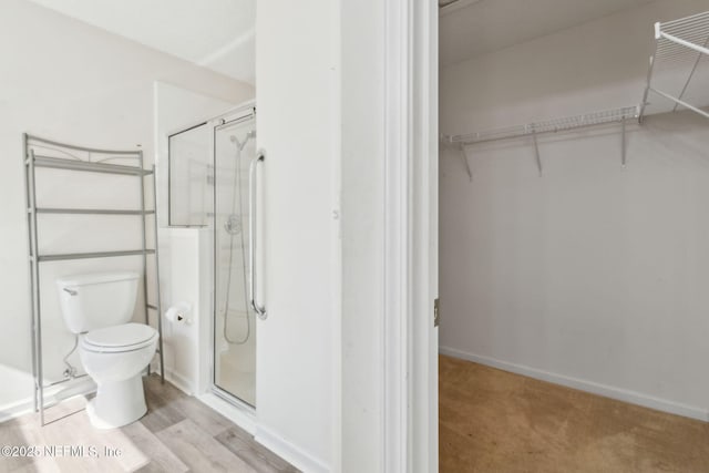 bathroom featuring toilet and a shower with shower door