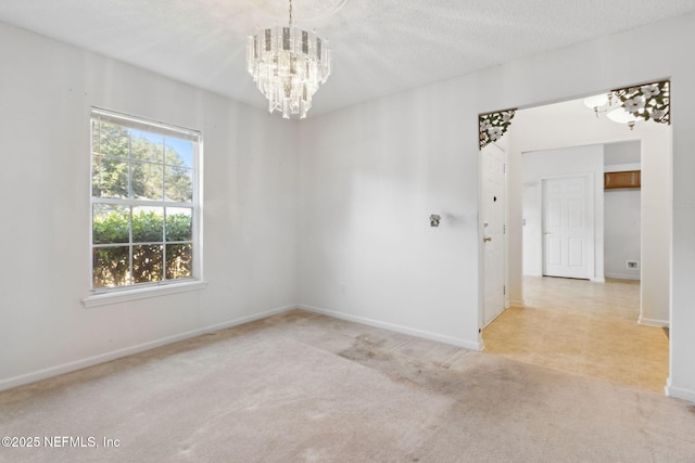 carpeted empty room with a textured ceiling and a chandelier