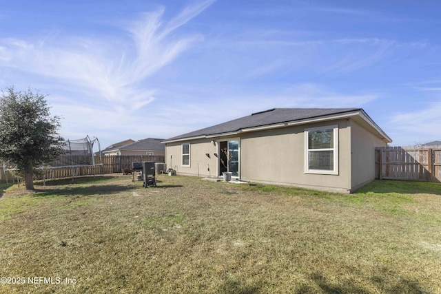 back of property with a yard and a trampoline