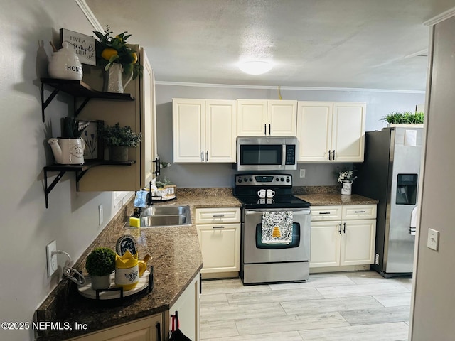 kitchen with ornamental molding, appliances with stainless steel finishes, sink, and dark stone countertops