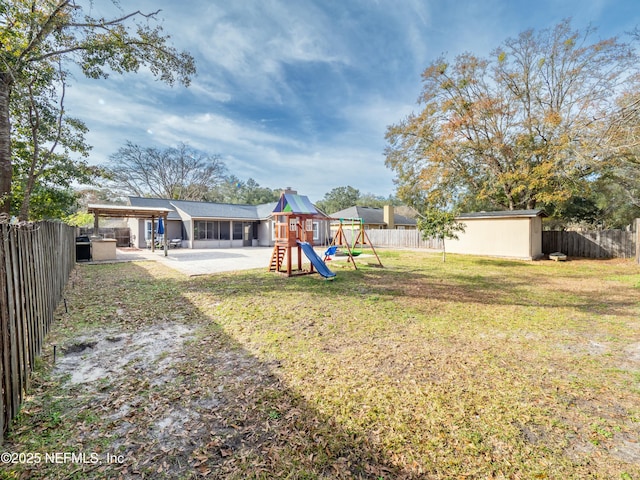 view of yard featuring a storage shed, a patio, and a playground