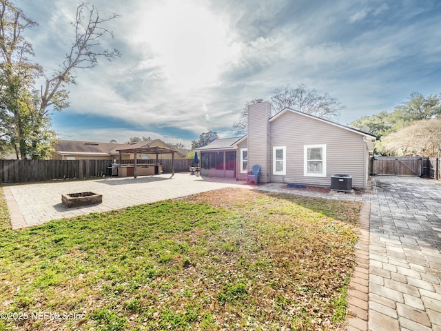 exterior space featuring a patio, a lawn, an outdoor fire pit, a sunroom, and central AC