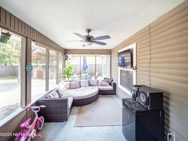 sunroom featuring a healthy amount of sunlight, a wood stove, and ceiling fan