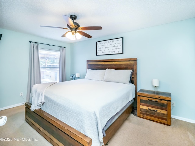 bedroom with ceiling fan, light colored carpet, and a textured ceiling