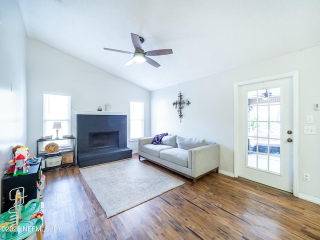 living room with hardwood / wood-style floors, vaulted ceiling, a brick fireplace, and ceiling fan