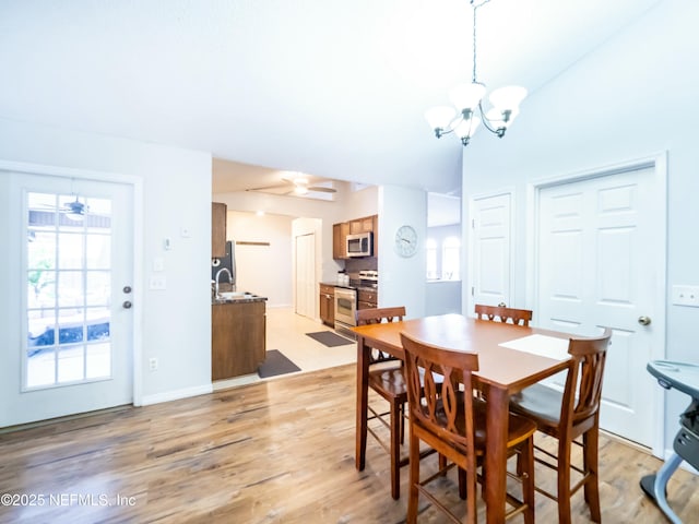 dining area with ceiling fan with notable chandelier, sink, and light hardwood / wood-style flooring