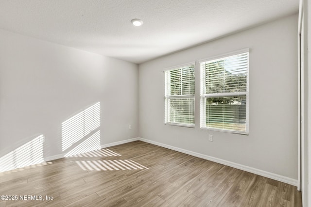 empty room with wood-type flooring and a textured ceiling