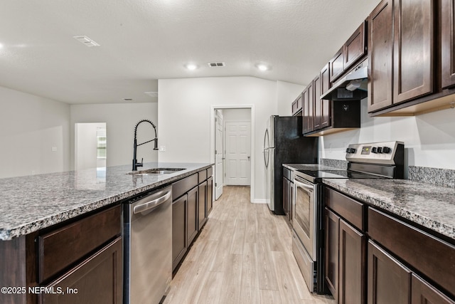 kitchen with an island with sink, sink, dark brown cabinetry, stainless steel appliances, and light wood-type flooring