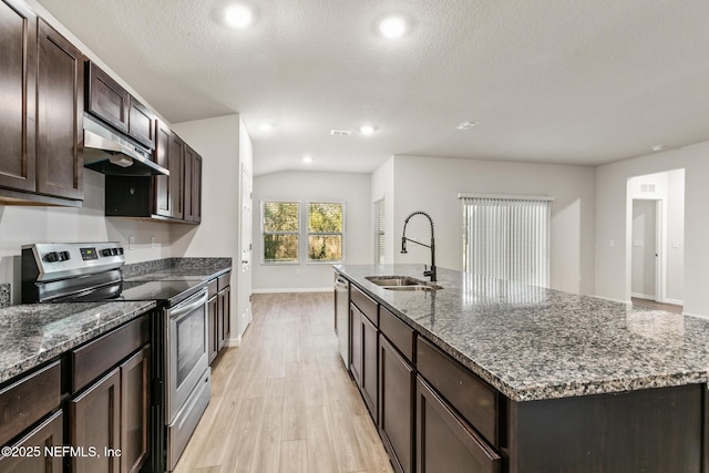 kitchen with appliances with stainless steel finishes, sink, dark stone countertops, a kitchen island with sink, and light hardwood / wood-style floors