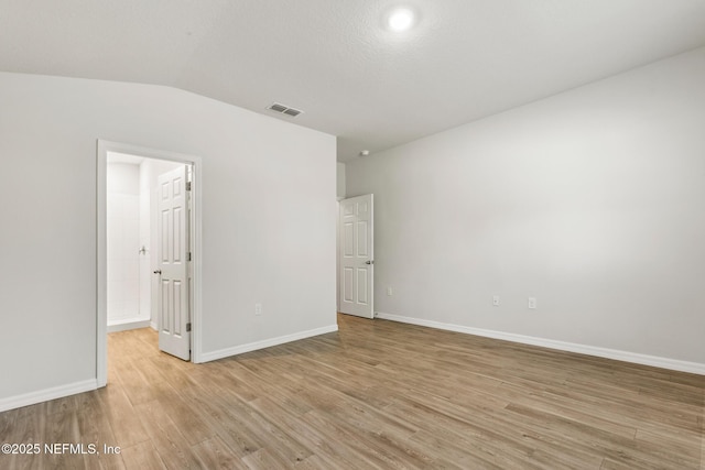 empty room featuring vaulted ceiling and light hardwood / wood-style flooring