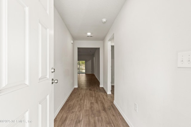 corridor with hardwood / wood-style floors and a textured ceiling