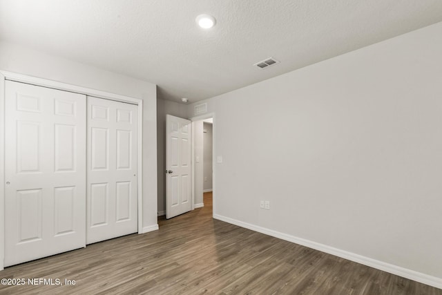 unfurnished bedroom featuring wood-type flooring, a closet, and a textured ceiling