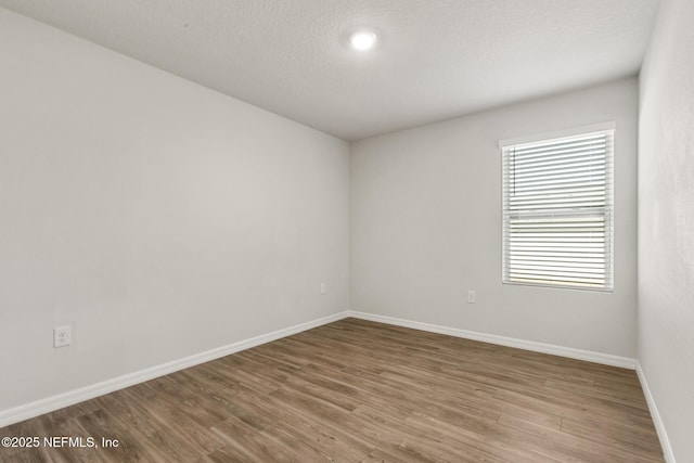 unfurnished room featuring hardwood / wood-style flooring and a textured ceiling