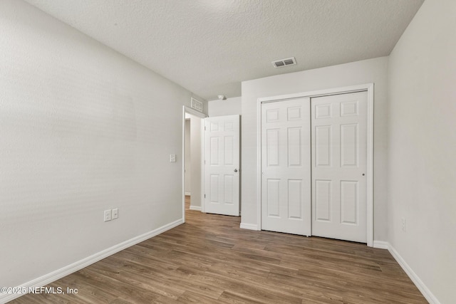 unfurnished bedroom featuring hardwood / wood-style flooring, a textured ceiling, and a closet