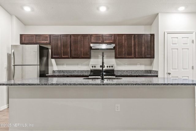 kitchen featuring dark brown cabinets, sink, a center island with sink, and stainless steel fridge