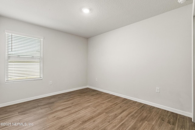 empty room featuring wood-type flooring and a textured ceiling