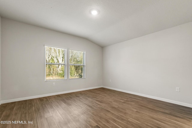 empty room featuring dark wood-type flooring and lofted ceiling