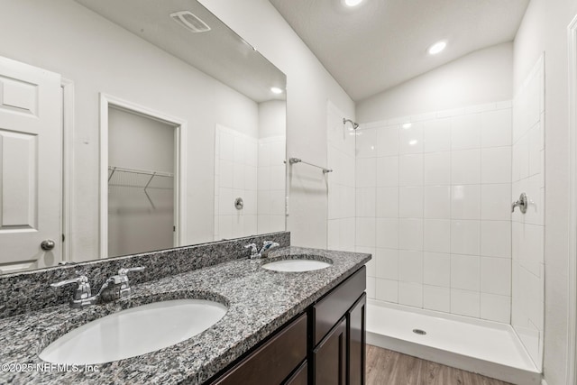 bathroom with vanity, lofted ceiling, and a tile shower