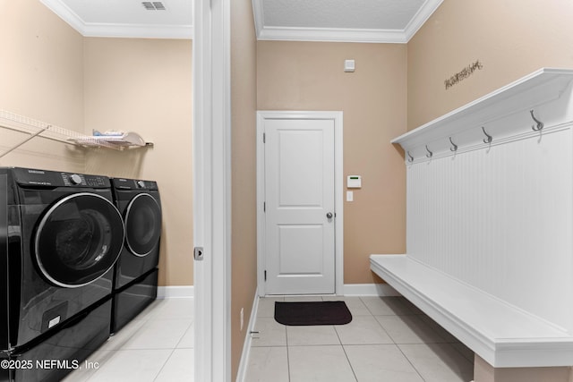 washroom featuring washing machine and dryer, ornamental molding, and light tile patterned floors