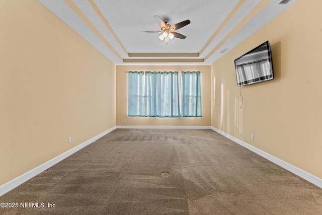 carpeted empty room with a textured ceiling, a raised ceiling, and ceiling fan