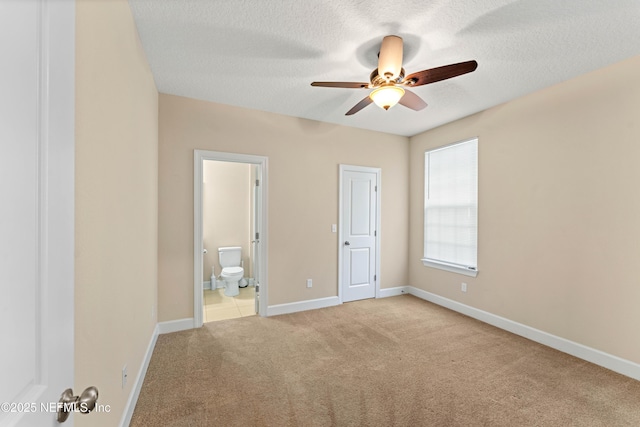 unfurnished bedroom featuring ceiling fan, light carpet, a textured ceiling, and ensuite bath