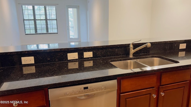 kitchen featuring dark stone counters, dishwasher, and sink