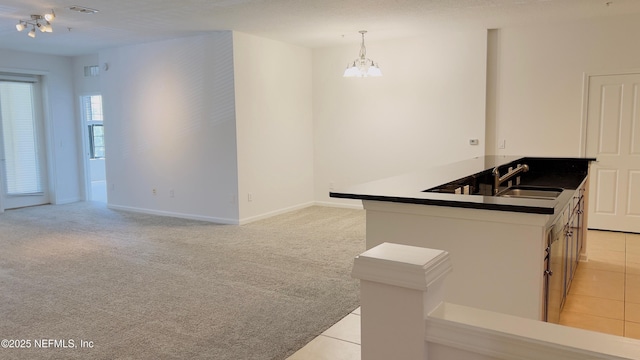 kitchen featuring sink, decorative light fixtures, a chandelier, light carpet, and kitchen peninsula