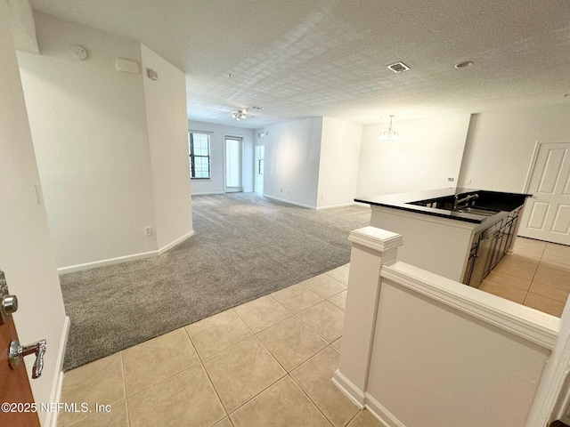 interior space featuring light carpet, sink, a notable chandelier, and a textured ceiling