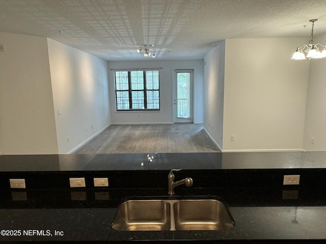 kitchen featuring an inviting chandelier, sink, decorative light fixtures, and a textured ceiling