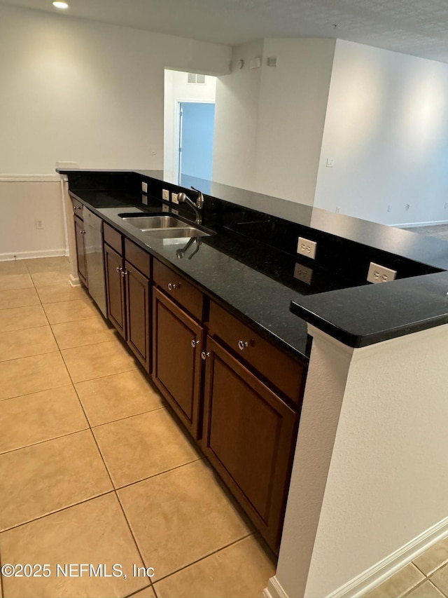 kitchen with light tile patterned flooring, sink, white dishwasher, and dark stone counters