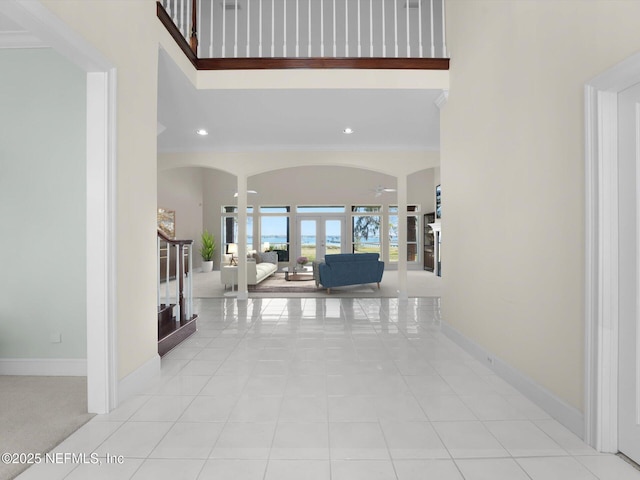 corridor with light tile patterned floors, a towering ceiling, and french doors