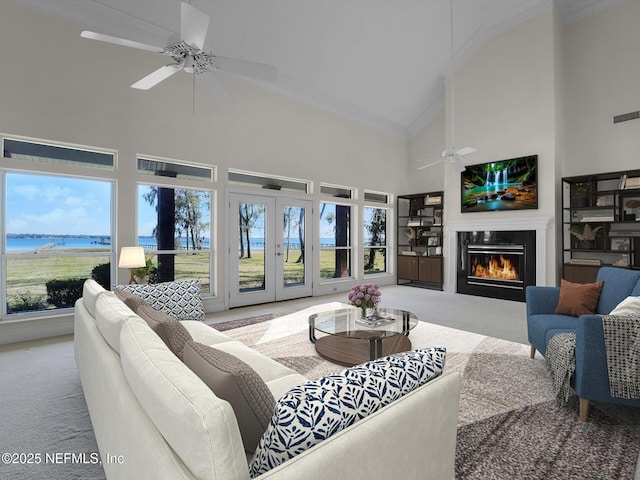 living room featuring a water view, crown molding, high vaulted ceiling, ceiling fan, and light colored carpet