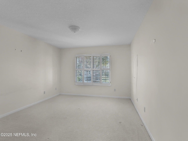 spare room featuring light carpet and a textured ceiling