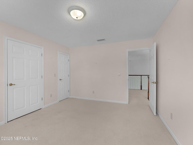 unfurnished bedroom featuring light carpet and a textured ceiling