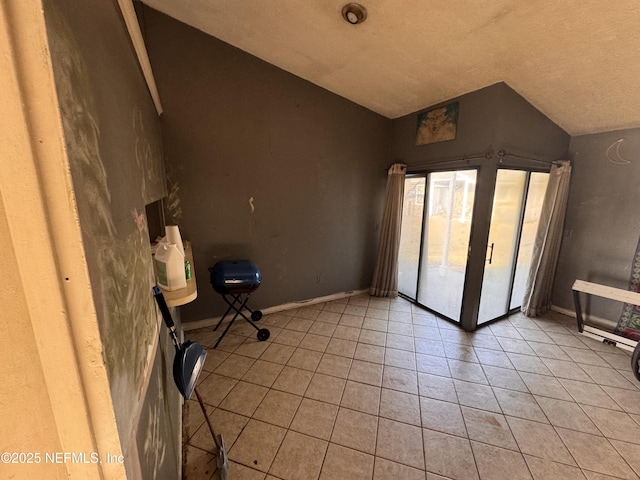 empty room featuring vaulted ceiling and light tile patterned floors