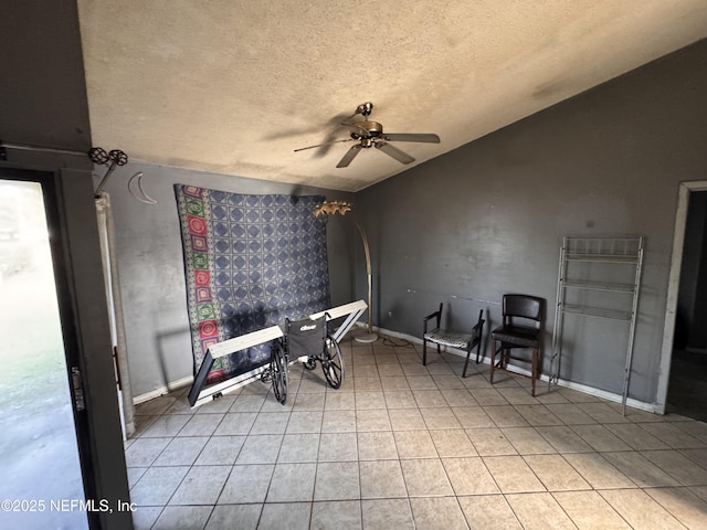 interior space with vaulted ceiling, light tile patterned floors, a textured ceiling, and ceiling fan