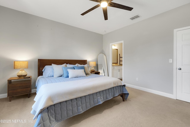 bedroom with ceiling fan, light colored carpet, and ensuite bath